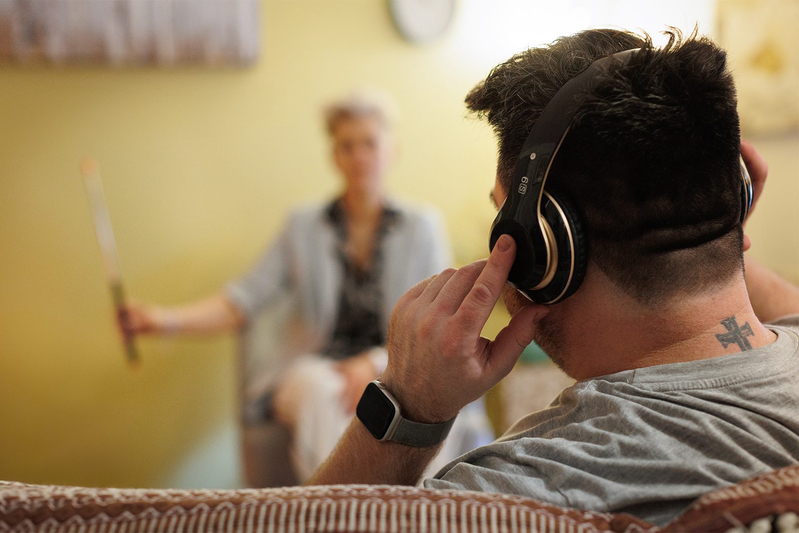 A man wearing headphones while sitting in front of another woman.