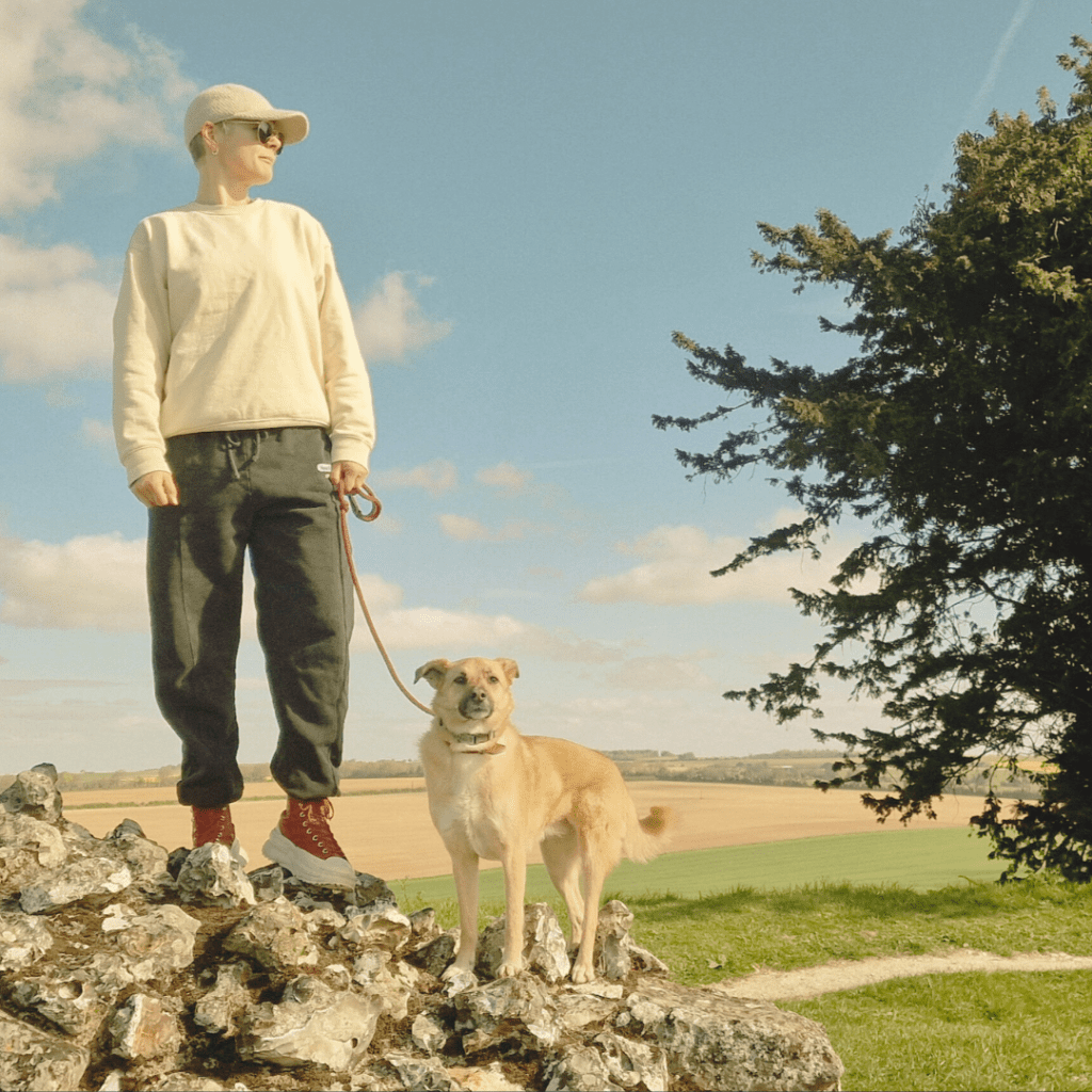 A man and his dog stand on top of a rock.